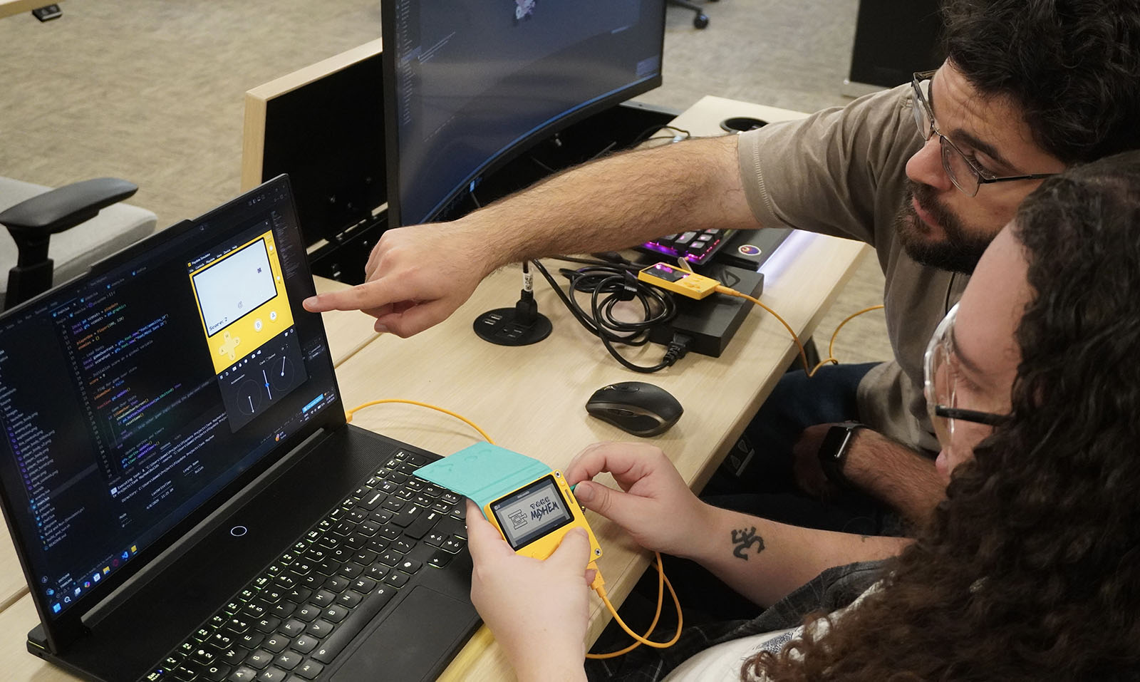 Two Duke GDDI students collaborate on designing a game for the Playdate handheld game console.