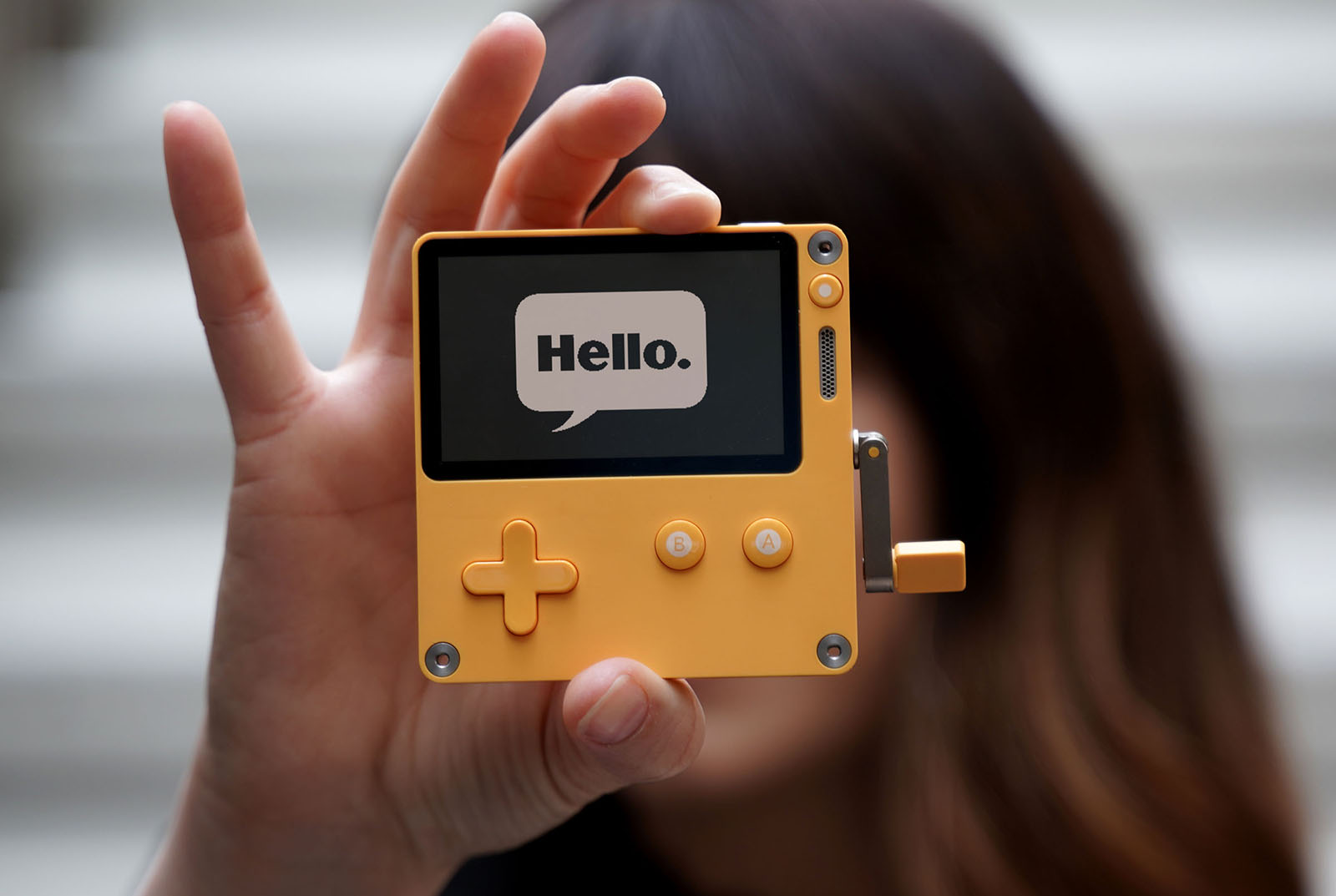 A woman holding the Playdate handheld game console.