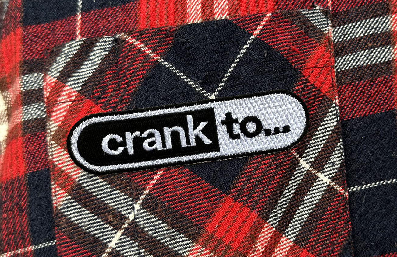 Plaid shirt pocket with a patch on it saying Crank to…